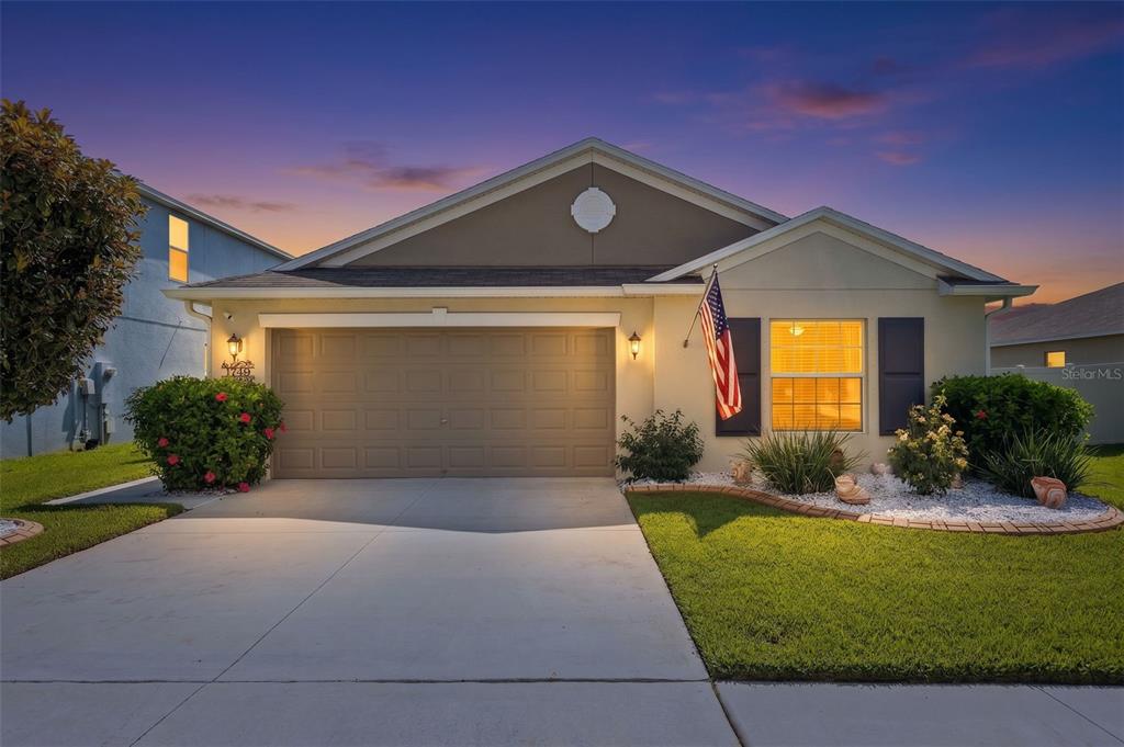 A single-story suburban house with a two-car garage, a front lawn, and an American flag — 1749 BROAD WINGED HAWK DRIVE, RUSKIN, FL