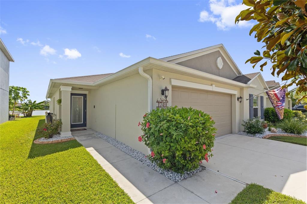 A single-story house with a beige stucco exterior, a two-car garage, and a front lawn — 1749 BROAD WINGED HAWK DRIVE, RUSKIN, FL