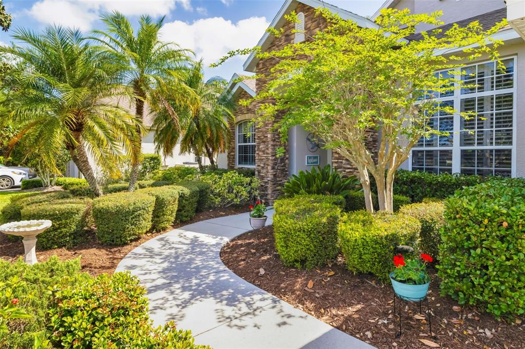 A curved concrete walkway leads to the stone-accented front entrance of a house with landscaping — 3839 59TH AVENUE CIRCLE E, ELLENTON, FL