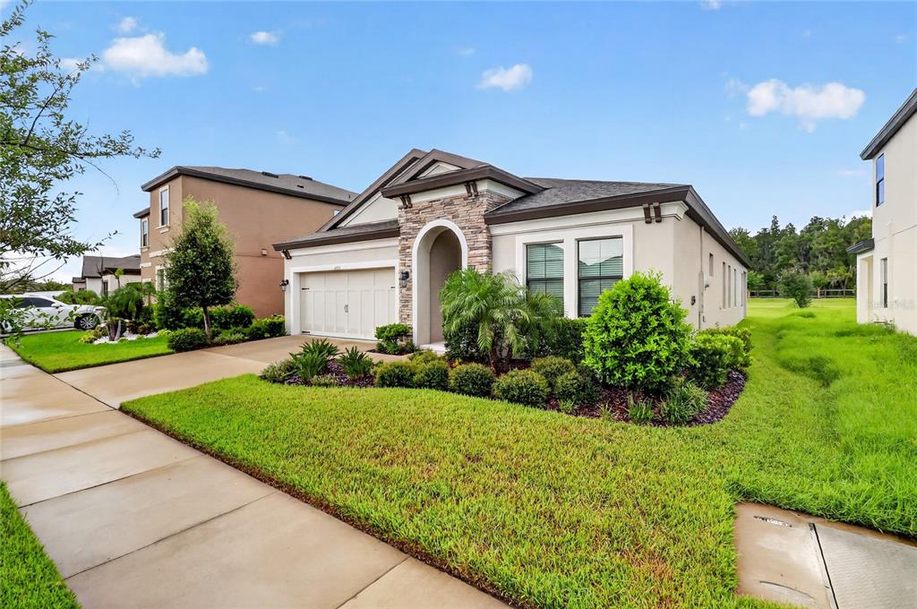 A single-story house with a stone-accented entryway, a two-car garage, and a manicured lawn — 12635 SHETLAND WALK DRIVE, LITHIA, FL