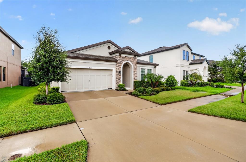 A single-story house with a two-car garage, stone entryway, and a concrete driveway — 12635 SHETLAND WALK DRIVE, LITHIA, FL