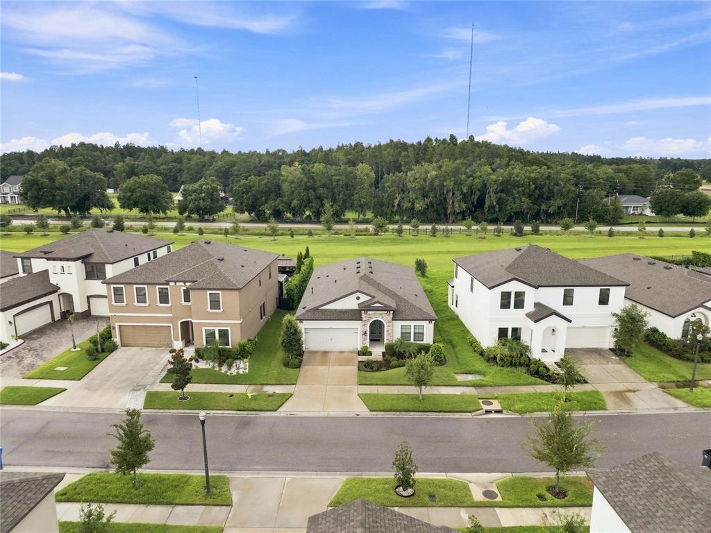 An aerial view shows three suburban houses with driveways and lawns facing a paved street — 12635 SHETLAND WALK DRIVE, LITHIA, FL