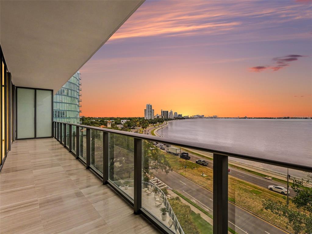 A balcony with tile flooring and a glass railing overlooks a coastal road and bay — 3101 W BAYSHORE STREET UNIT 503, TAMPA, FL