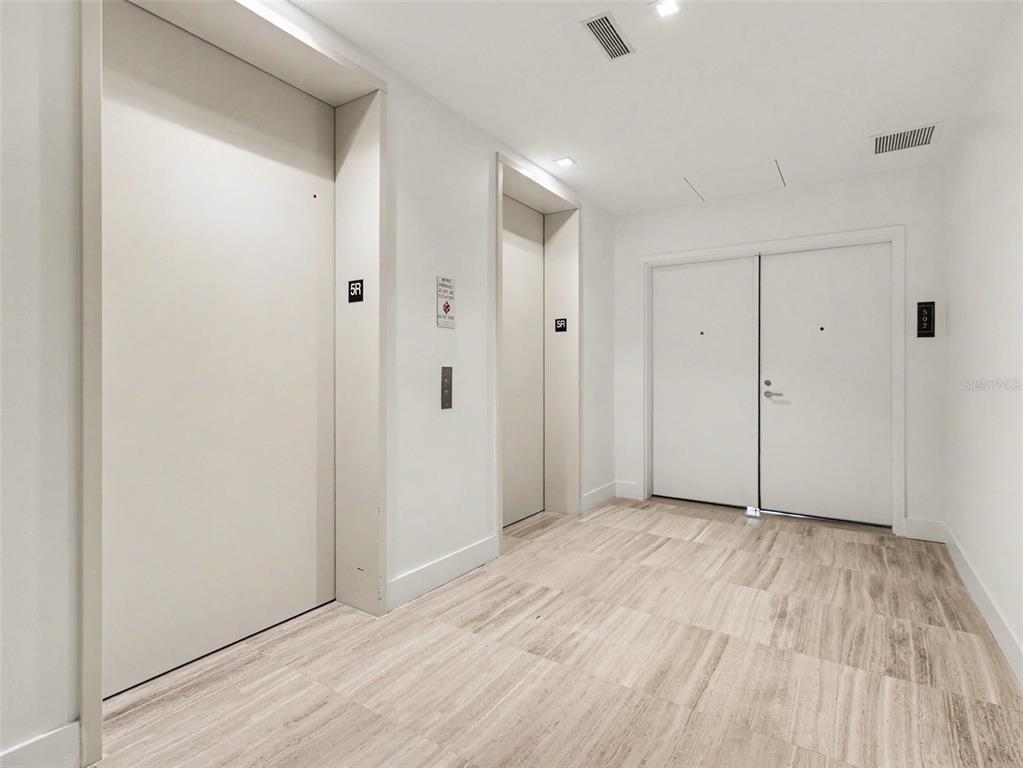 A hallway features two elevator doors and a double-door entrance with light wood-look flooring — 3101 W BAYSHORE STREET UNIT 503, TAMPA, FL