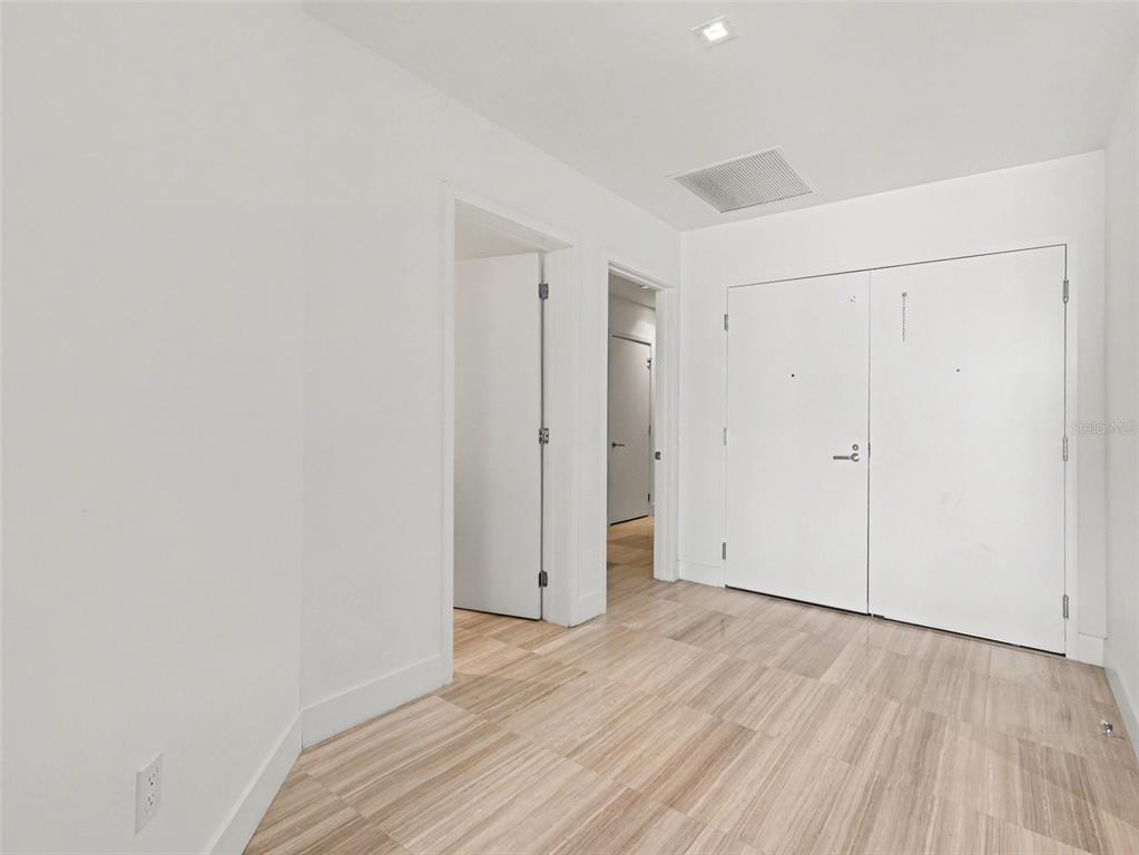 A room with white walls, light wood-look tile flooring, and two sets of white doors — 3101 W BAYSHORE STREET UNIT 503, TAMPA, FL