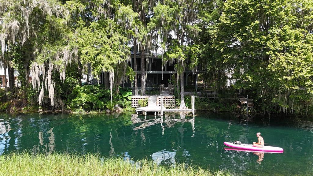A person paddles a pink kayak on a clear river in front of a house — 11685 E BLUE COVE DRIVE, DUNNELLON, FL