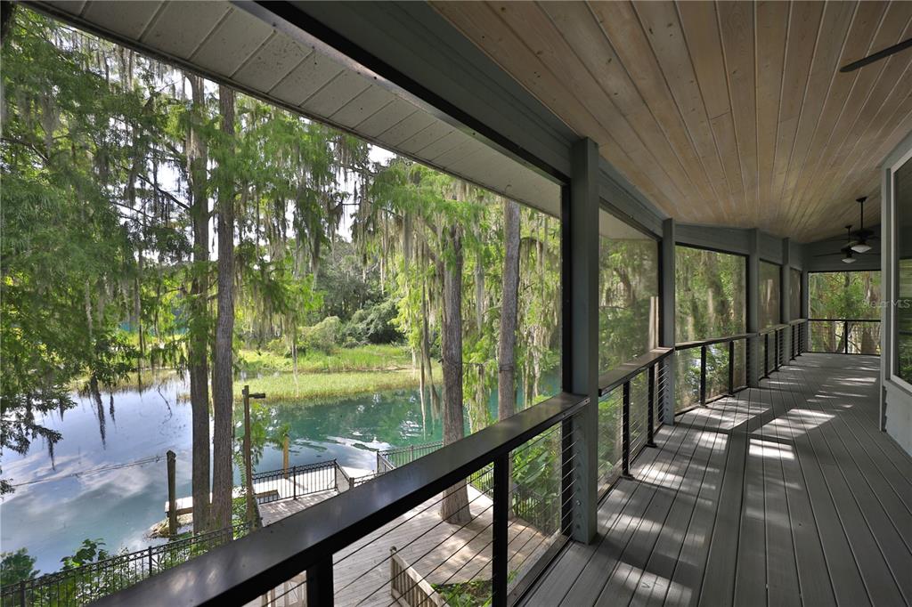 A screened-in wooden deck overlooks a river surrounded by trees with hanging Spanish moss — 11685 E BLUE COVE DRIVE, DUNNELLON, FL