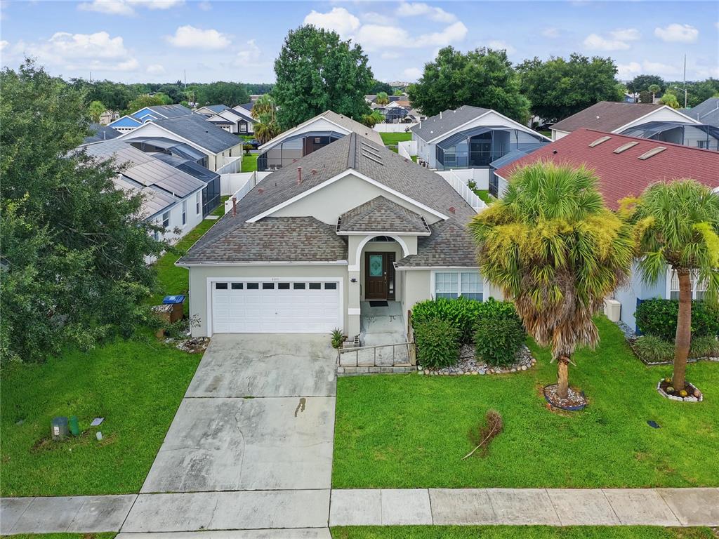 An aerial view of a single-story suburban house with a white garage and palm trees — 8105 SANTEE DRIVE, KISSIMMEE, FL