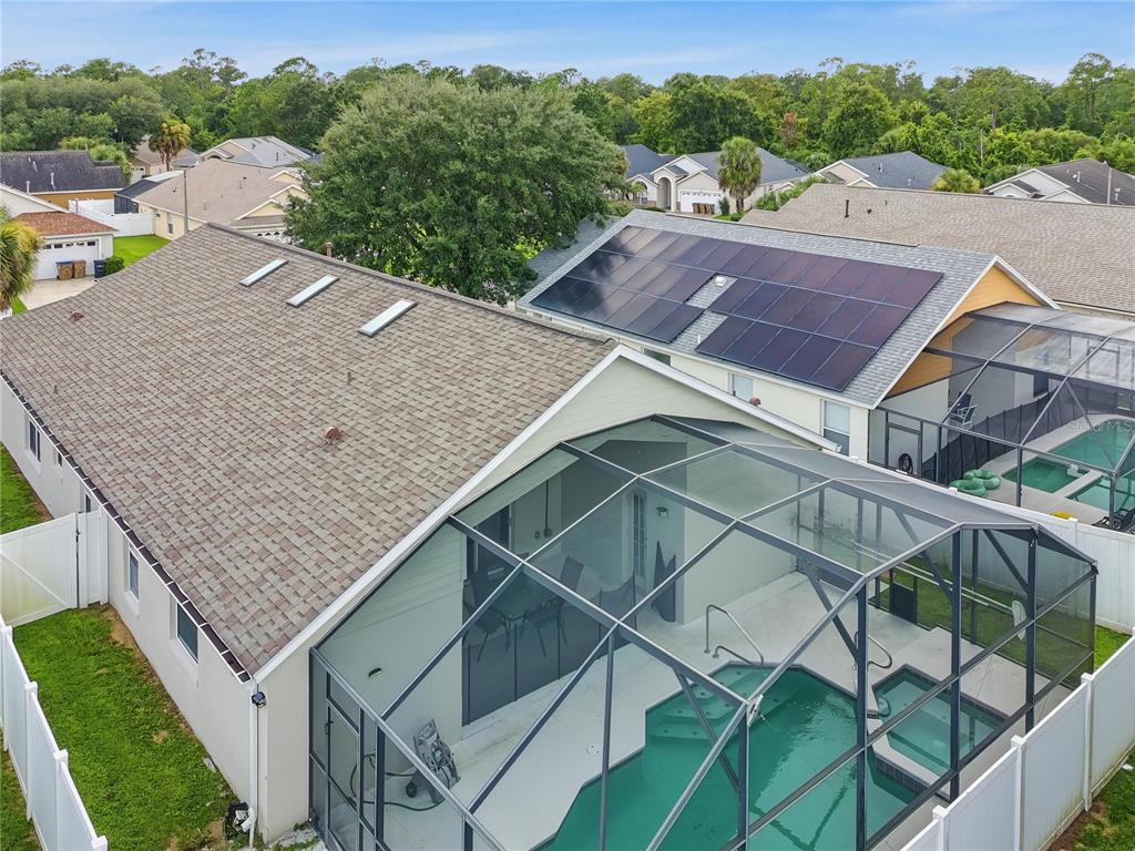An aerial view of a house with a screened-in pool, solar panels, and skylights — 8105 SANTEE DRIVE, KISSIMMEE, FL