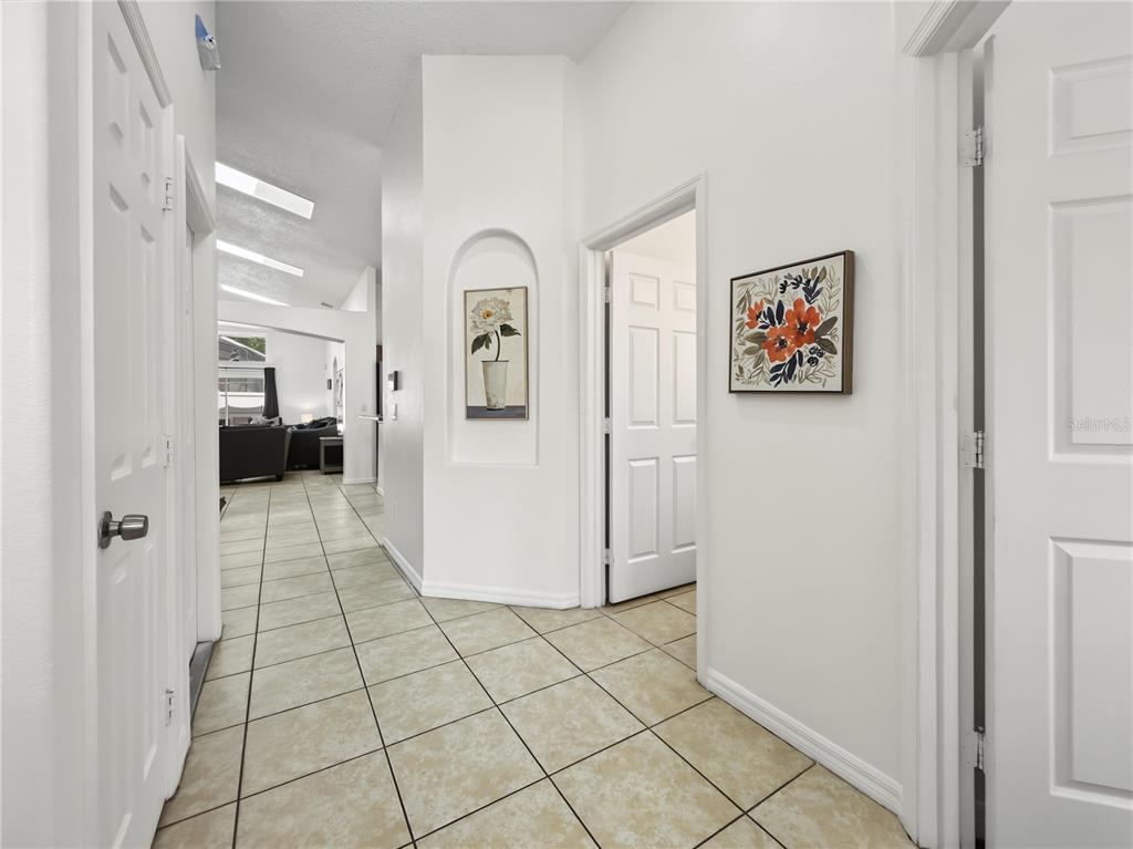 A tiled hallway leads toward a living area with vaulted ceilings and skylights — 8105 SANTEE DRIVE, KISSIMMEE, FL