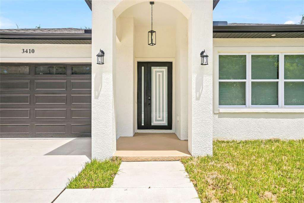 The exterior of a house features a dark garage door, a covered entryway, and windows — 3410 N 31ST STREET, TAMPA, FL