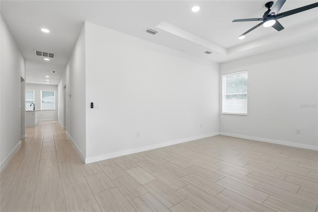 A bright, empty room features light-colored tile flooring, white walls, and a ceiling fan — 3410 N 31ST STREET, TAMPA, FL