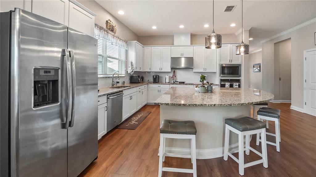 A kitchen features white cabinets, granite countertops, stainless steel appliances, and a central island — 16451 GOOD HEARTH BOULEVARD, CLERMONT, FL