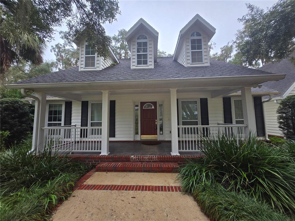 A white house with a covered front porch, brick steps, and three dormer windows — 436 SE 4TH AVENUE, MELROSE, FL