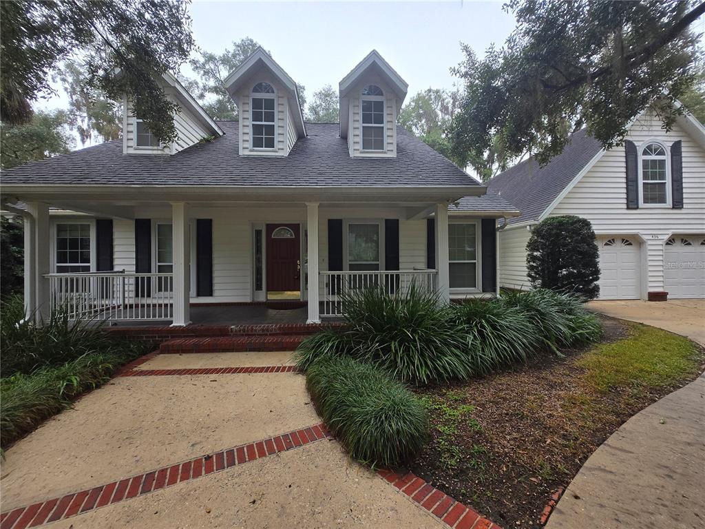 A white two-story house features a front porch, dormer windows, and an attached garage — 436 SE 4TH AVENUE, MELROSE, FL