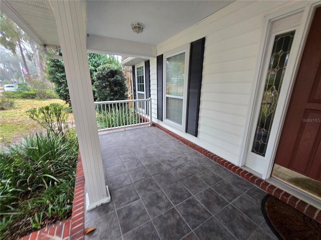A covered front porch features gray tiled flooring, white siding, and a brown front door — 436 SE 4TH AVENUE, MELROSE, FL