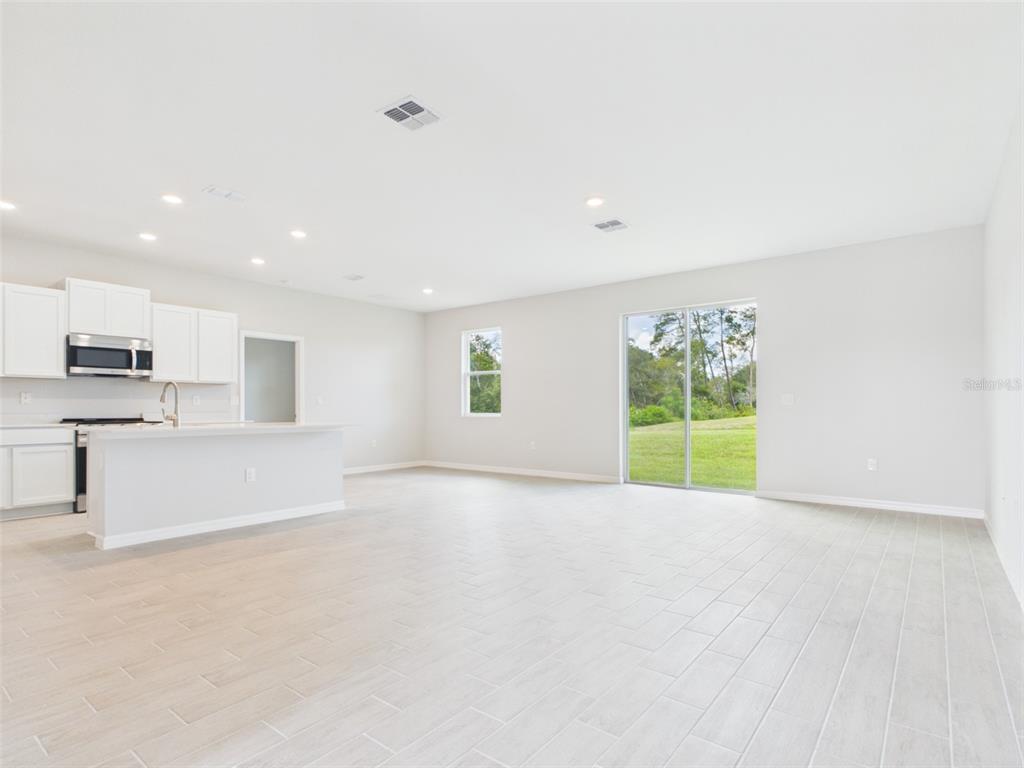 A bright hallway with light-colored tile flooring leads toward a glass sliding door — 16090 SW 42ND TERRACE, OCALA, FL