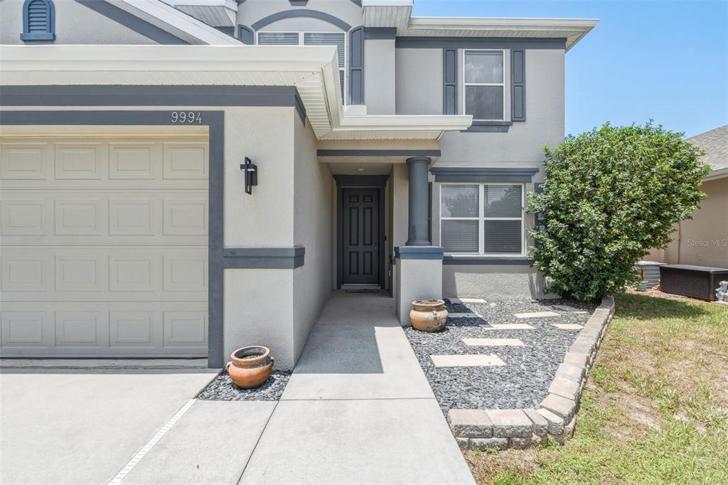 A two-story house exterior features a gray garage, a front entrance, and a stone walkway — 9994 SPRING GULCH LANE, PUNTA GORDA, FL