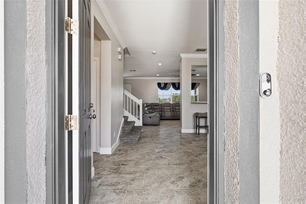 A view through an open front door into a tiled entryway with a carpeted staircase — 9994 SPRING GULCH LANE, PUNTA GORDA, FL