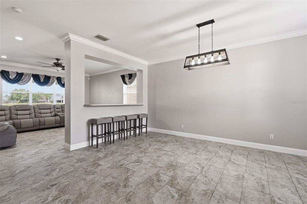 A dining area features gray tile flooring, a rectangular chandelier, and a breakfast bar counter — 9994 SPRING GULCH LANE, PUNTA GORDA, FL