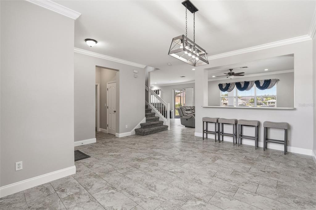 A tiled dining area features a modern chandelier, a breakfast bar, and a staircase — 9994 SPRING GULCH LANE, PUNTA GORDA, FL