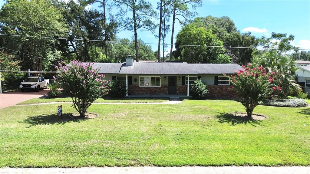 A single-story house with a brick facade, gray siding, and a front lawn with trees — 1815 SE 7TH AVENUE, OCALA, FL