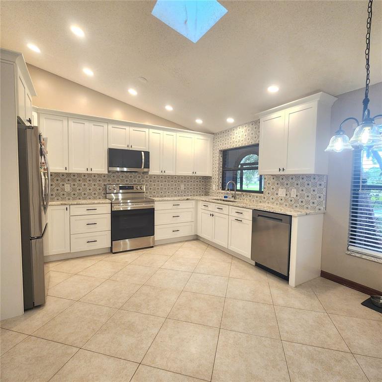 A kitchen with white cabinets, patterned backsplash, stainless steel dishwasher, and tile flooring — 2805 LAKE TOHOPEKALIGA BOULEVARD, KISSIMMEE, FL