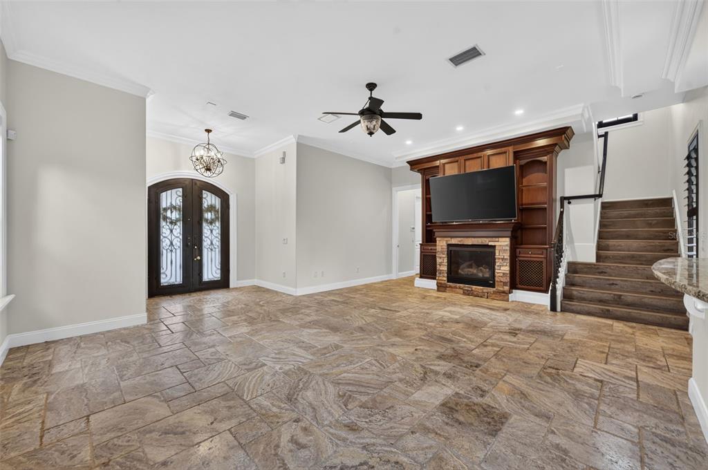 A living room features stone tile flooring, a fireplace with built-in shelving, and a staircase — 1570 PALMER AVENUE, WINTER PARK, FL