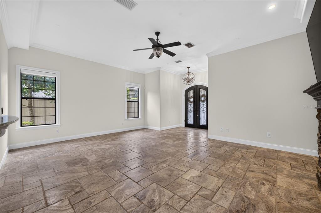 A spacious living room features light-colored walls, tile flooring, a ceiling fan, and double doors — 1570 PALMER AVENUE, WINTER PARK, FL