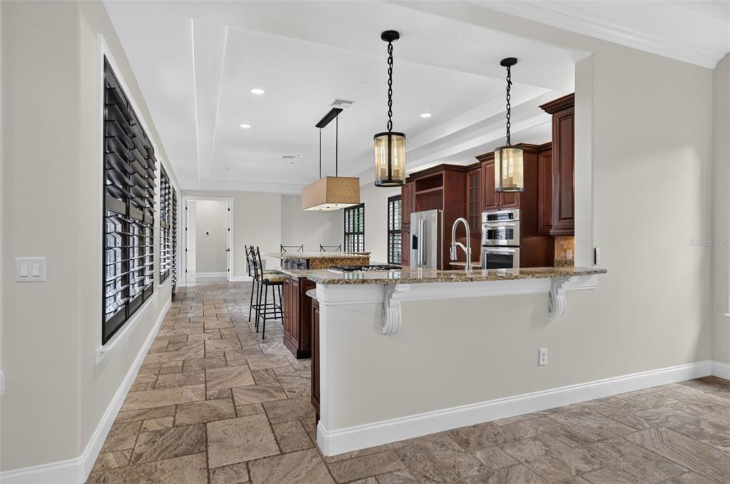 A kitchen with dark wood cabinets, granite countertops, a breakfast bar, and stone tile flooring — 1570 PALMER AVENUE, WINTER PARK, FL
