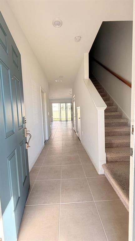 An entryway with tile flooring, a blue front door, and a carpeted staircase to the right — 4557 TEOLI COURT, KISSIMMEE, FL