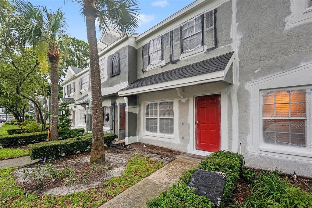 The exterior of a two-story townhouse features gray stucco walls and a red front door — 366 COUNTRYSIDE KEY BOULEVARD, OLDSMAR, FL