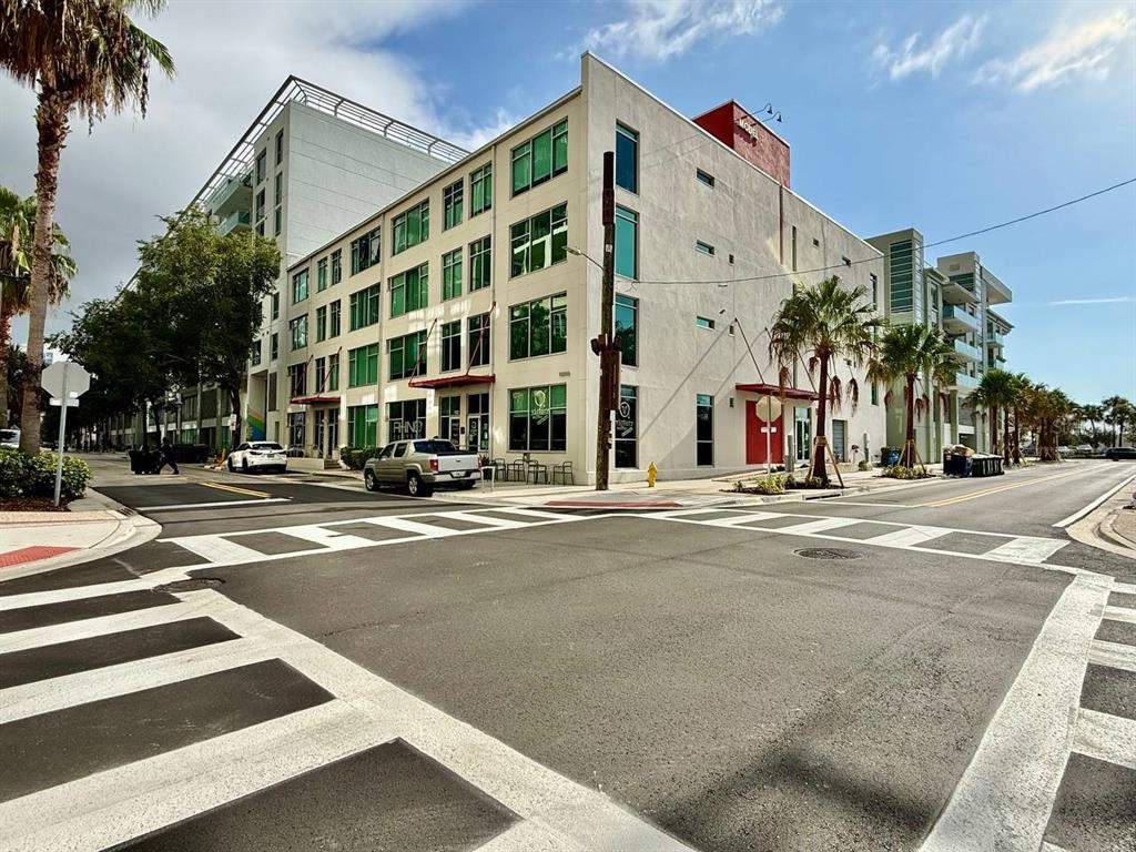 A multi-story apartment building stands on a street corner with a crosswalk in the foreground — 101 N 12TH STREET UNIT 305, TAMPA, FL