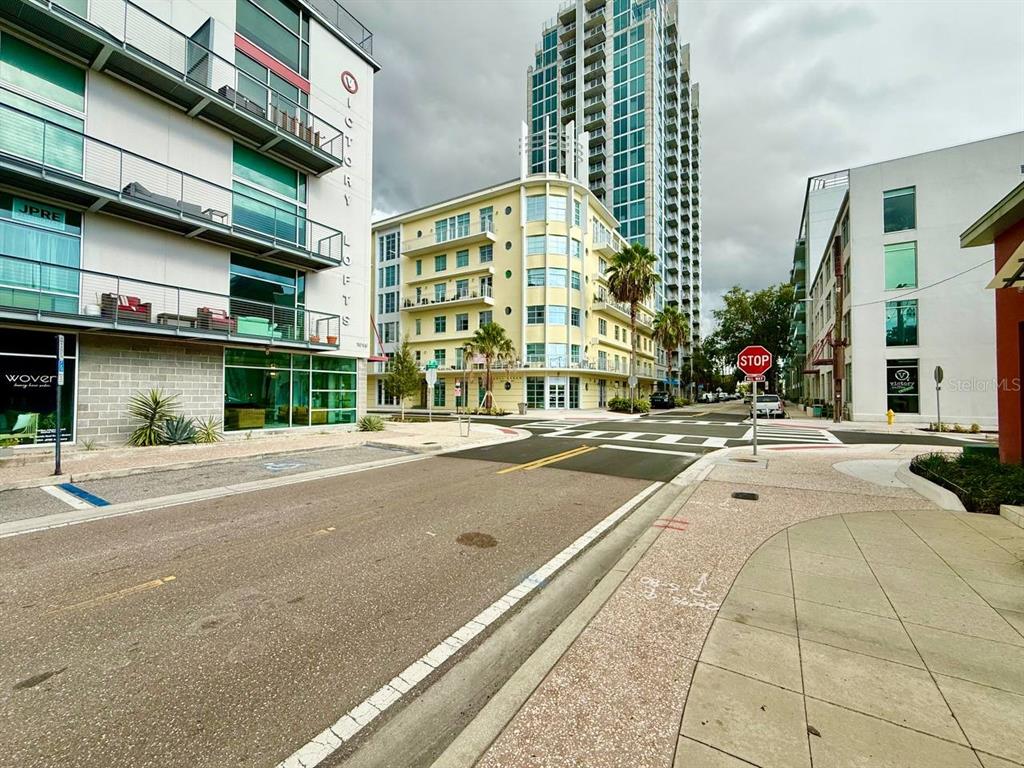 A street-level view of a modern urban intersection with apartment buildings and a stop sign — 101 N 12TH STREET UNIT 305, TAMPA, FL