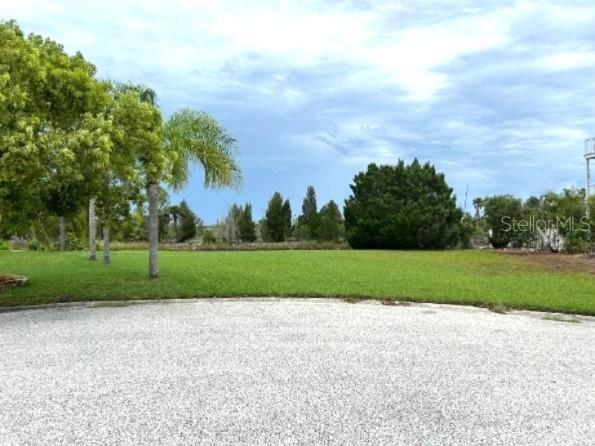 A gravel driveway leads to a grassy lot with palm trees and distant foliage — 3335 CROAKER DRIVE, HERNANDO BEACH, FL