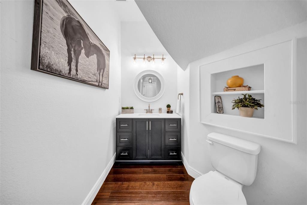 A modern powder room features a dark vanity, round mirror, and a recessed wall niche — 17930 DORMAN ROAD, LITHIA, FL