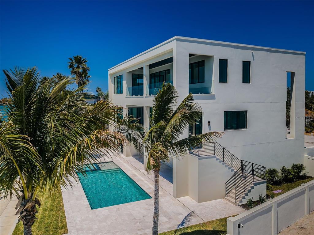 A modern white multi-story house features a swimming pool, palm trees, and an outdoor staircase — 236 HOWARD DRIVE, BELLEAIR BEACH, FL