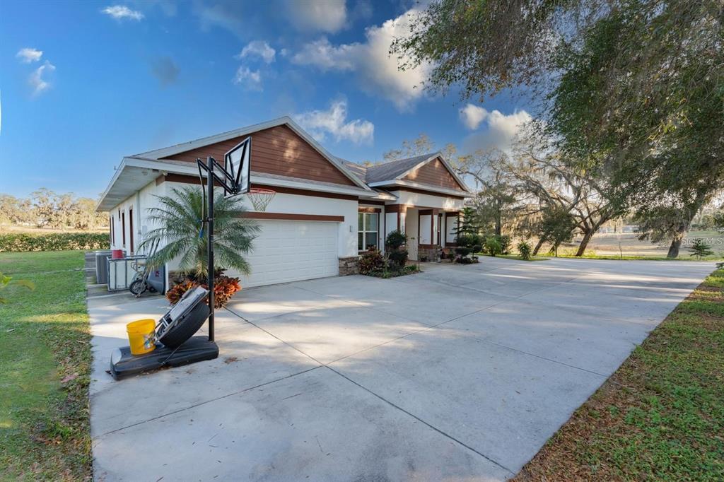A single-story house with a white exterior, brown gables, and a large concrete driveway — 9606 RIPLEY ROAD, THONOTOSASSA, FL