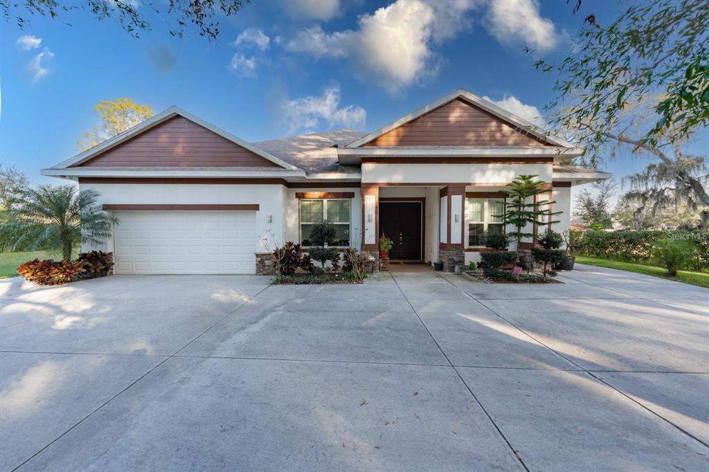 A single-story house with a white stucco exterior, brown gables, and a concrete driveway — 9606 RIPLEY ROAD, THONOTOSASSA, FL