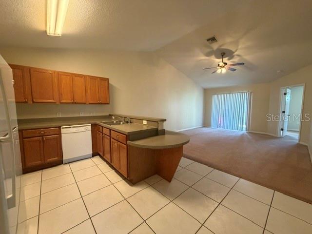 A kitchen with wood cabinets and tile flooring opens to a carpeted living area — 33 E ST LOUIS AVENUE, EUSTIS, FL