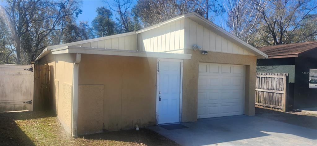 A tan, single-story detached garage with a white door and a white roll-up garage door — 4839 BILLY DIRECT LANE, LUTZ, FL