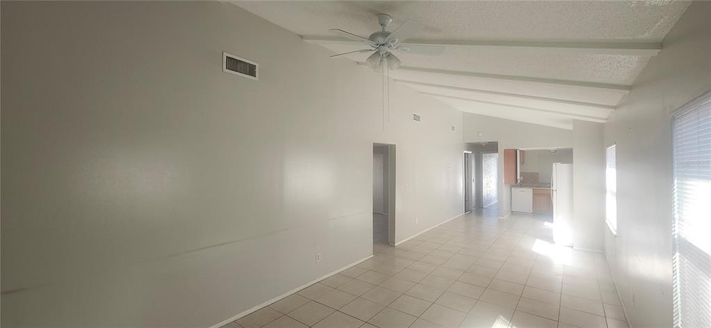 A bright, open-concept living area features white walls, tiled floors, and a vaulted ceiling — 4839 BILLY DIRECT LANE, LUTZ, FL