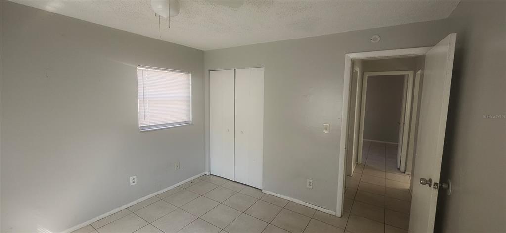 A bedroom with light gray walls, white closet doors, and light-colored tile flooring — 4839 BILLY DIRECT LANE, LUTZ, FL