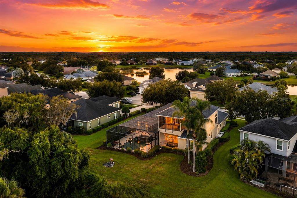 An aerial view of a suburban house with a screened-in pool at sunset — 1568 HICKORY VIEW CIRCLE, PARRISH, FL
