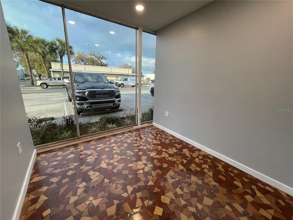 An interior room with large windows, gray walls, and a patterned tile floor — 201 E MAIN STREET UNIT 101, LEESBURG, FL