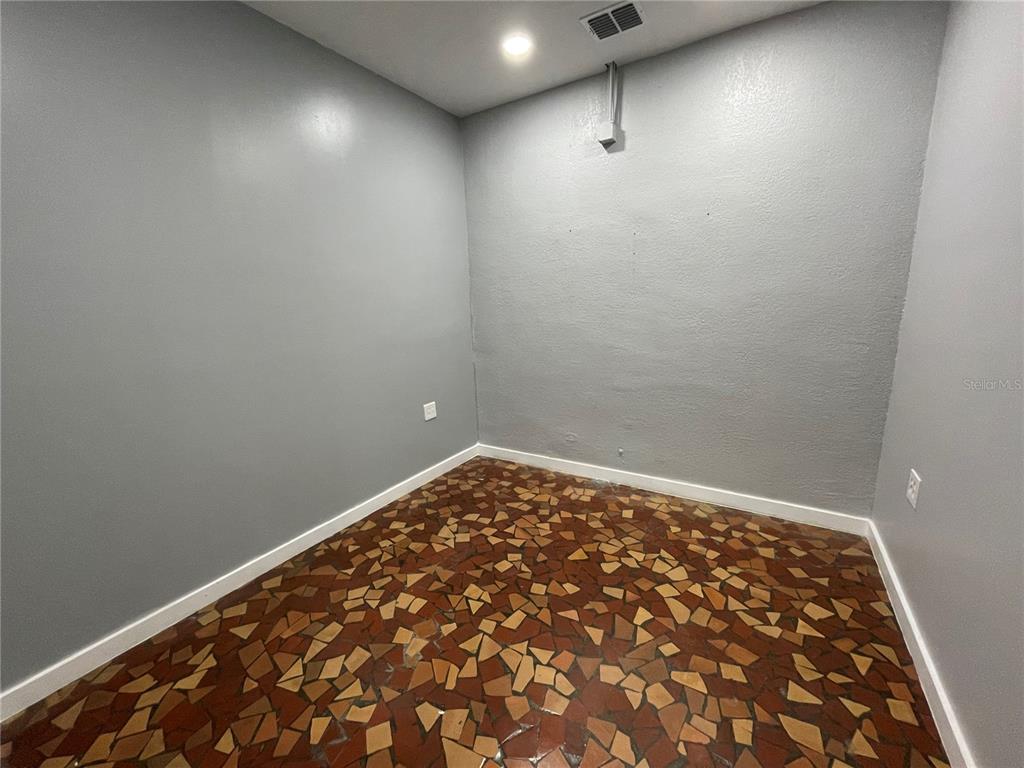 An empty room with gray walls and a brown mosaic-style tile floor — 201 E MAIN STREET UNIT 101, LEESBURG, FL