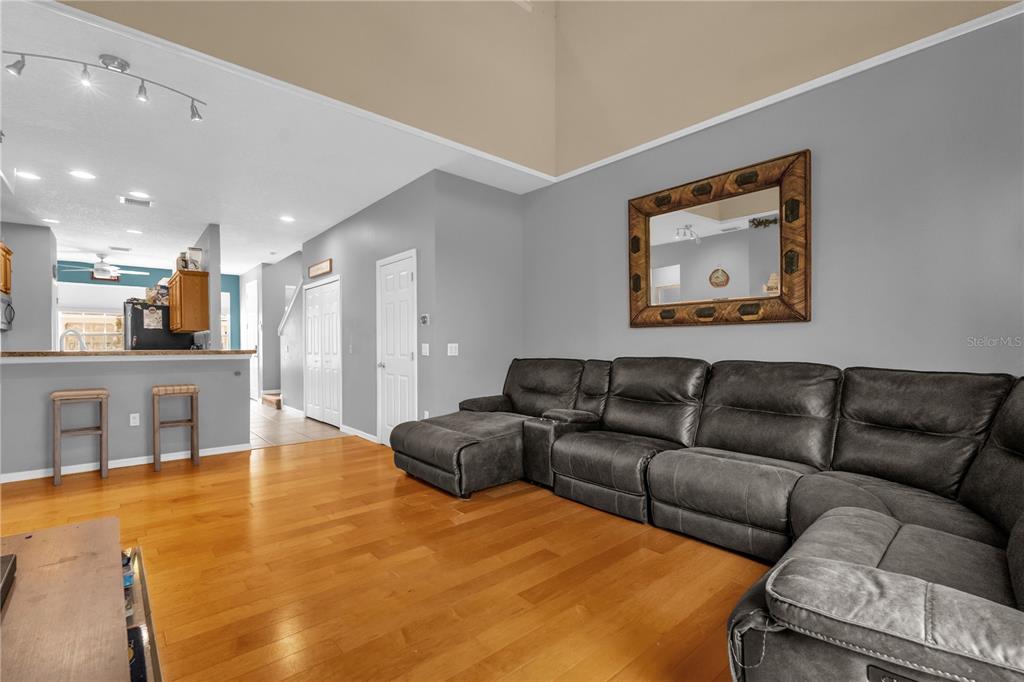A living room features hardwood floors, a large grey sectional sofa, and a high ceiling — 4981 ALITA TERRACE, ST CLOUD, FL