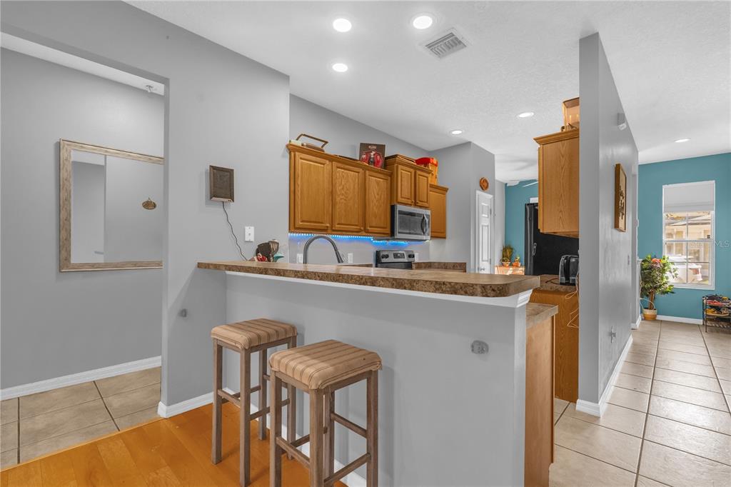 A kitchen with wood cabinets, a breakfast bar with two stools, and tile flooring — 4981 ALITA TERRACE, ST CLOUD, FL