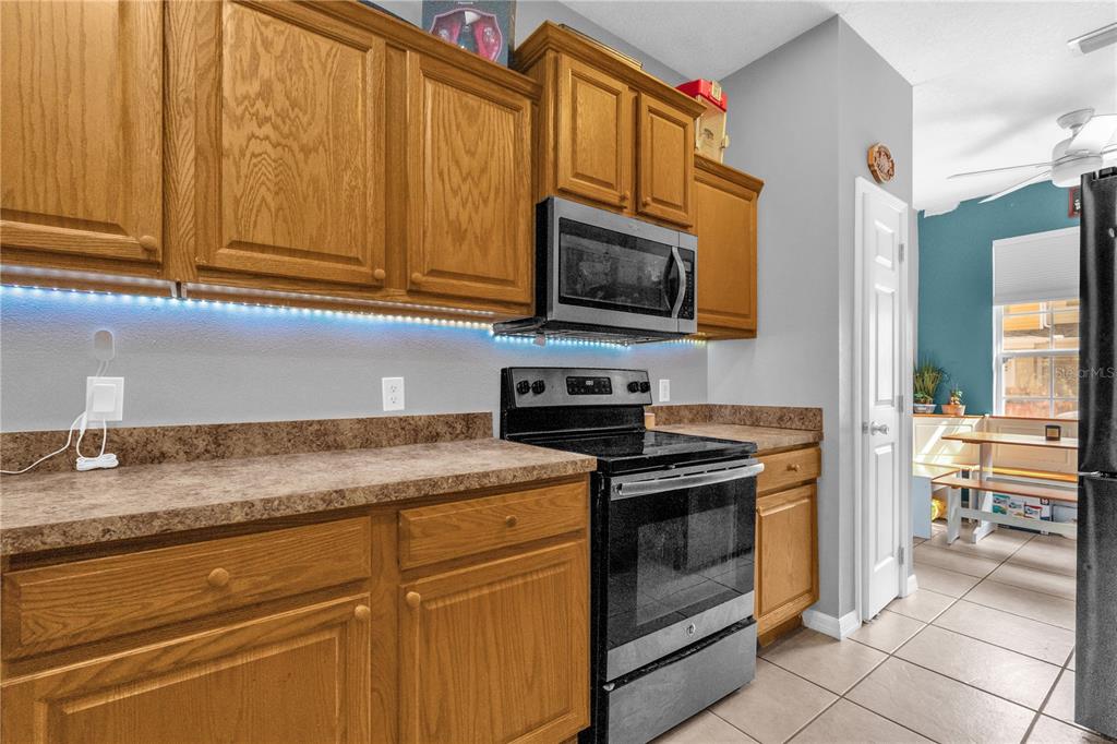 A kitchen features oak cabinets, a black stove, a microwave, and brown laminate countertops — 4981 ALITA TERRACE, ST CLOUD, FL
