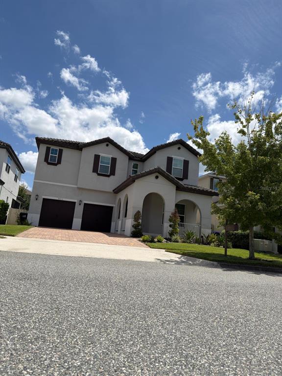 A two-story suburban house with a two-car garage, arched entryway, and brown shutters — 8713 CRESCENDO AVENUE, WINDERMERE, FL